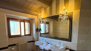 Un bagno con soffitto in legno, uno specchio grande, due lavabi, un water e una vasca da bagno.