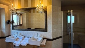 Un bagno con due lavandini, uno specchio grande, un lampadario e una cabina doccia in vetro.