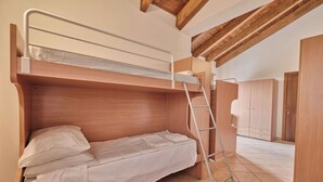 Una cama litera con escalera, cabecero de madera y un colchón blanco.