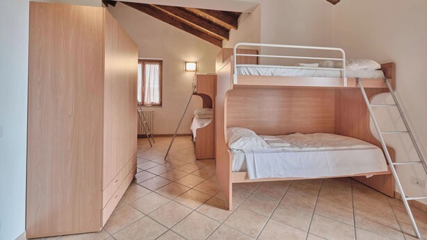 Habitación con literas, un armario de madera y una escalera.
