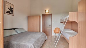 Habitación pequeña con literas, cama individual, armario y una silla.