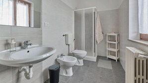Un baño moderno con lavamanos, bidé, inodoro y zona de ducha.