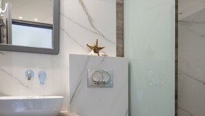 Ett modernt badrum med en tvättställsskiva i marmor, en toalett och en duschkabin med glasväggar.