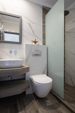 A modern bathroom with a marble vanity, a toilet, and a glass shower enclosure. - Studio Johanna A2 by Rentals Pro - Toroni Halkidiki (Toroni)