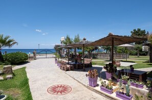 A patio area with outdoor seating, a decorative tile pattern, and a view of the sea. - Studio Johanna A2 by Rentals Pro - Toroni Halkidiki (Toroni)