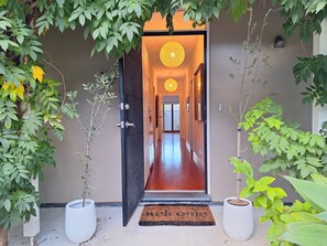 A hallway with a door leading to a room, potted plants on either side, and a doormat at the entrance. - Cute & cosy family home - close to the city (Brompton)