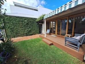 Une maison moderne dotée d’un patio couvert, d’une pelouse et d’une grande baie vitrée.