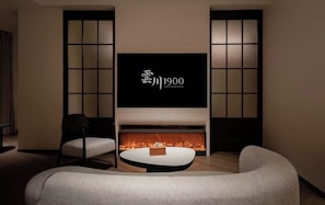 Una sala de estar moderna con un televisor de pantalla plana sobre una chimenea, un sofá y un sillón.