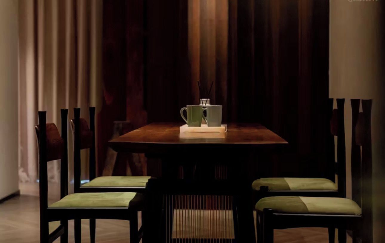 Een eettafel met stoelen, een vaas en een kaars.