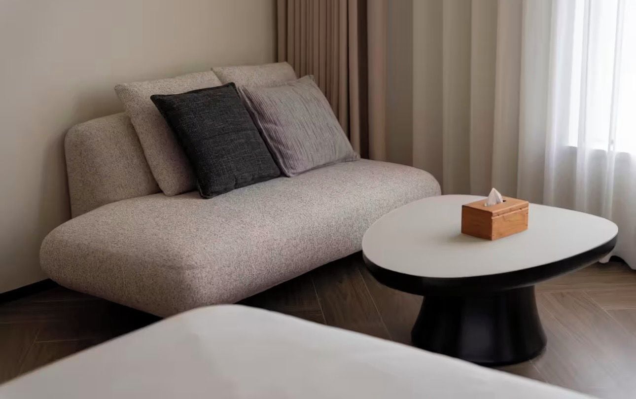 A modern living room with a sofa, a round coffee table, and a tissue box.