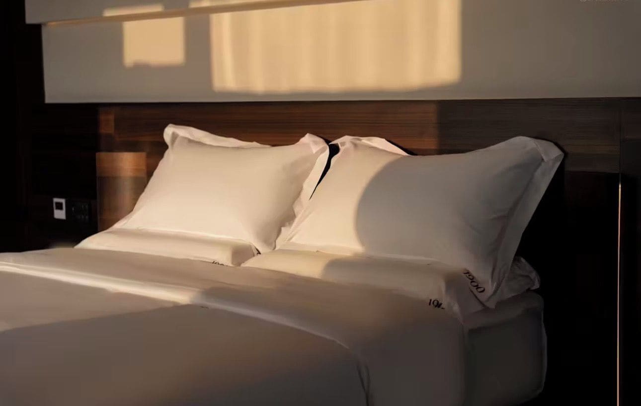 Una cama con ropa de cama blanca y cabecera de madera.