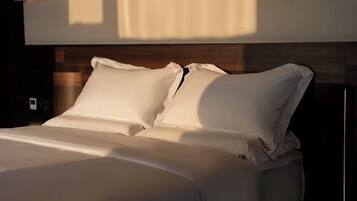Una cama con ropa de cama blanca y cabecera de madera.