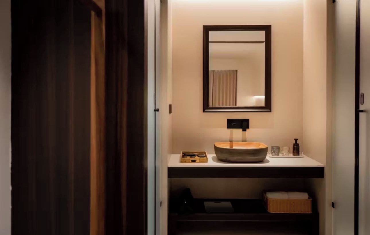 Een badkamer met een houten wasbak, een spiegel en een plank met toiletartikelen.