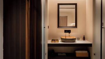 Een badkamer met een houten wasbak, een spiegel en een plank met toiletartikelen.
