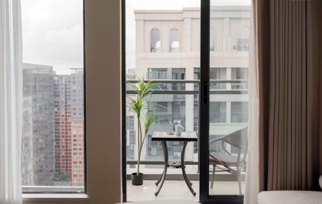 A balcony with a potted plant, a small table with a cup, and a chair.