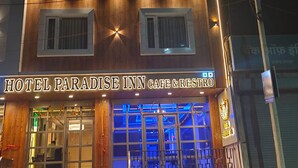 A multi-story building with a sign reading 'HOTEL PARADISE INN CAFE & RESTRO'.