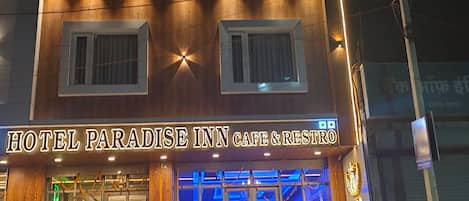 A multi-story building with a sign reading 'HOTEL PARADISE INN CAFE & RESTRO'.