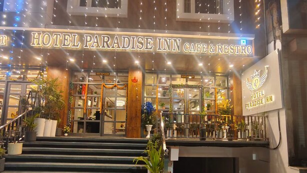 The entrance to the HOTEL PARADISE INN with a reception desk, glass doors, and a staircase leading to the entrance.
