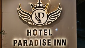 A sign for the Paradise Inn with a logo featuring a crown and wings.