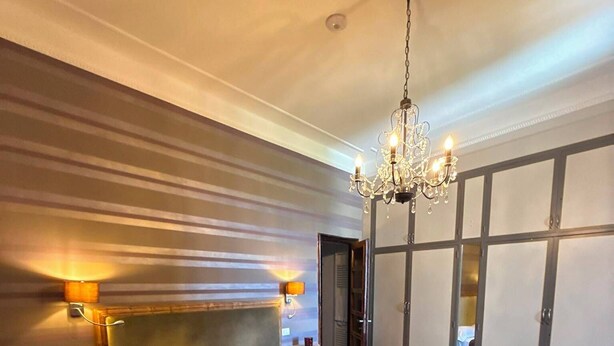 Ein Schlafzimmer mit einem großen Bett, einer Chandelier, einem Kleiderschrank und einem Nachttisch mit Lampe.