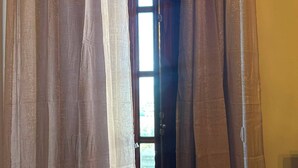 Ein Durchgang mit transparenten Vorhängen, ein sichtbares Fenster und eine Treppe, die zu einer oberen Ebene führt.