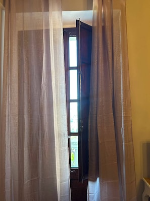 Una puerta con cortinas translúcidas, una ventana a la vista y una escalera que sube a un nivel superior.