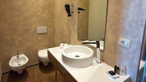 Ein modernes Badezimmer mit Bidet, Toilette, Waschbecken und Spiegel.
