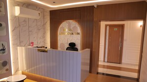 Zona de recepción de un hotel, con mostrador, cartel de recepción y un cartel con el número de la sala.