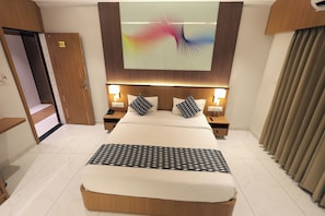 A hotel room with a large bed, two bedside tables, a wall-mounted TV, and a door with a number.