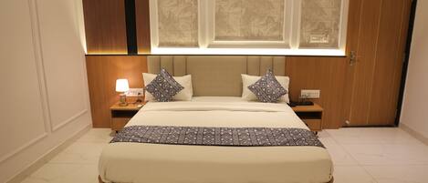 Un dormitorio con una cama grande, dos mesitas de noche, una mesita auxiliar, una lámpara y una ventana con vistas.