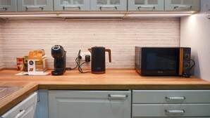 A kitchen with a coffee maker, a kettle, and a microwave on the counter.