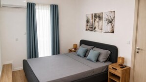 A modern bedroom with a bed, curtains, bedside tables, and wall art.