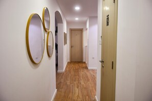 A hallway with wooden flooring, white walls, and three gold-framed mirrors. - Coastal Oasis (Wied il-Għajn)