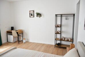 A bedroom with a bed, a desk with a chair, a wardrobe, and a small trash bin. - Coastal Oasis (Wied il-Għajn)