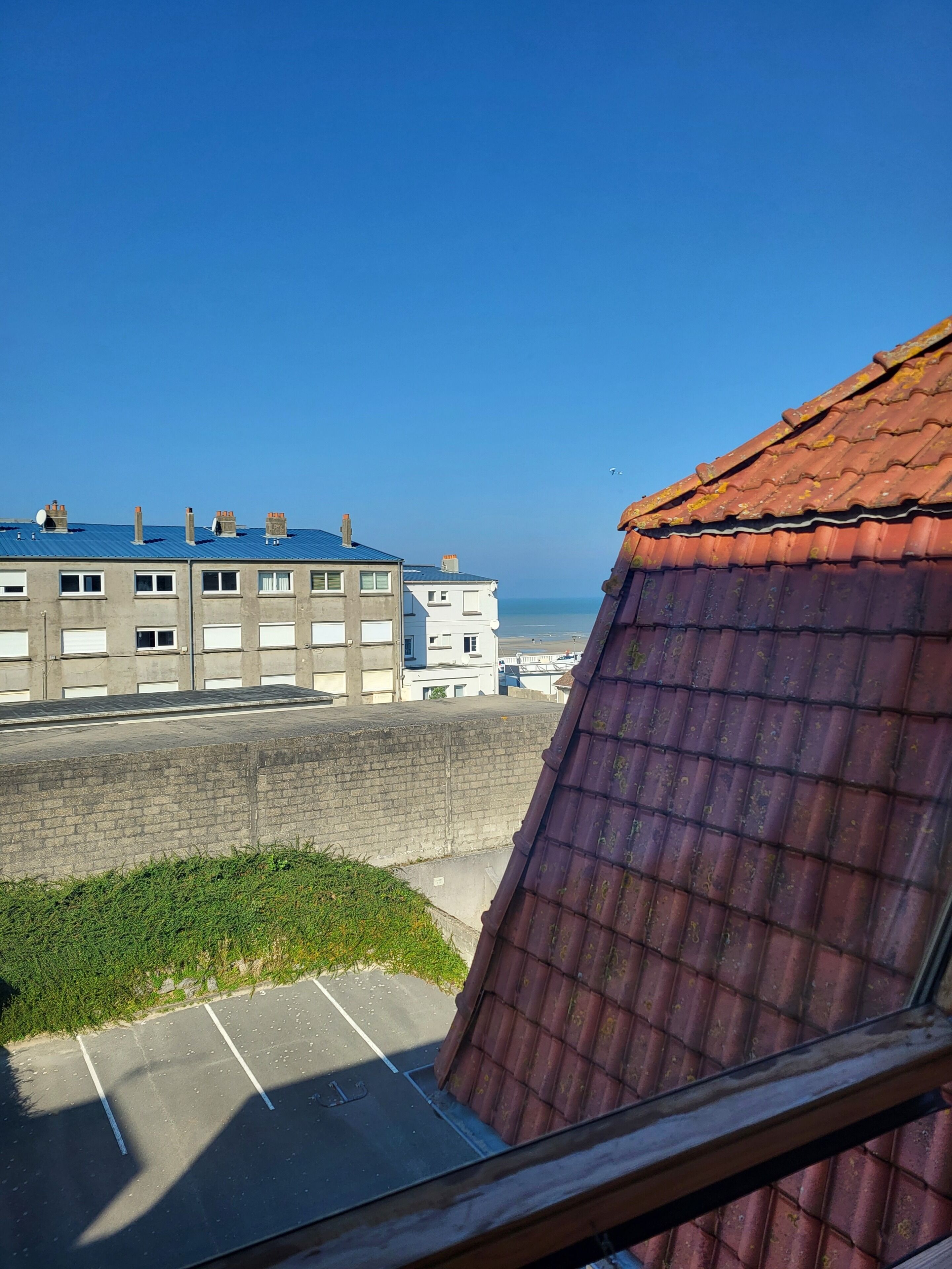 A view of a building with a red roof and a parking lot in the foreground.