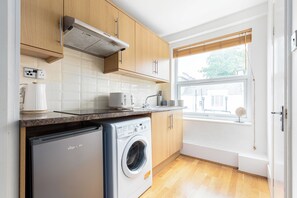 Eine kompakte Küche mit Holzausstattung, integriertem Geschirrspüler und einem Fenster mit Ausblick.