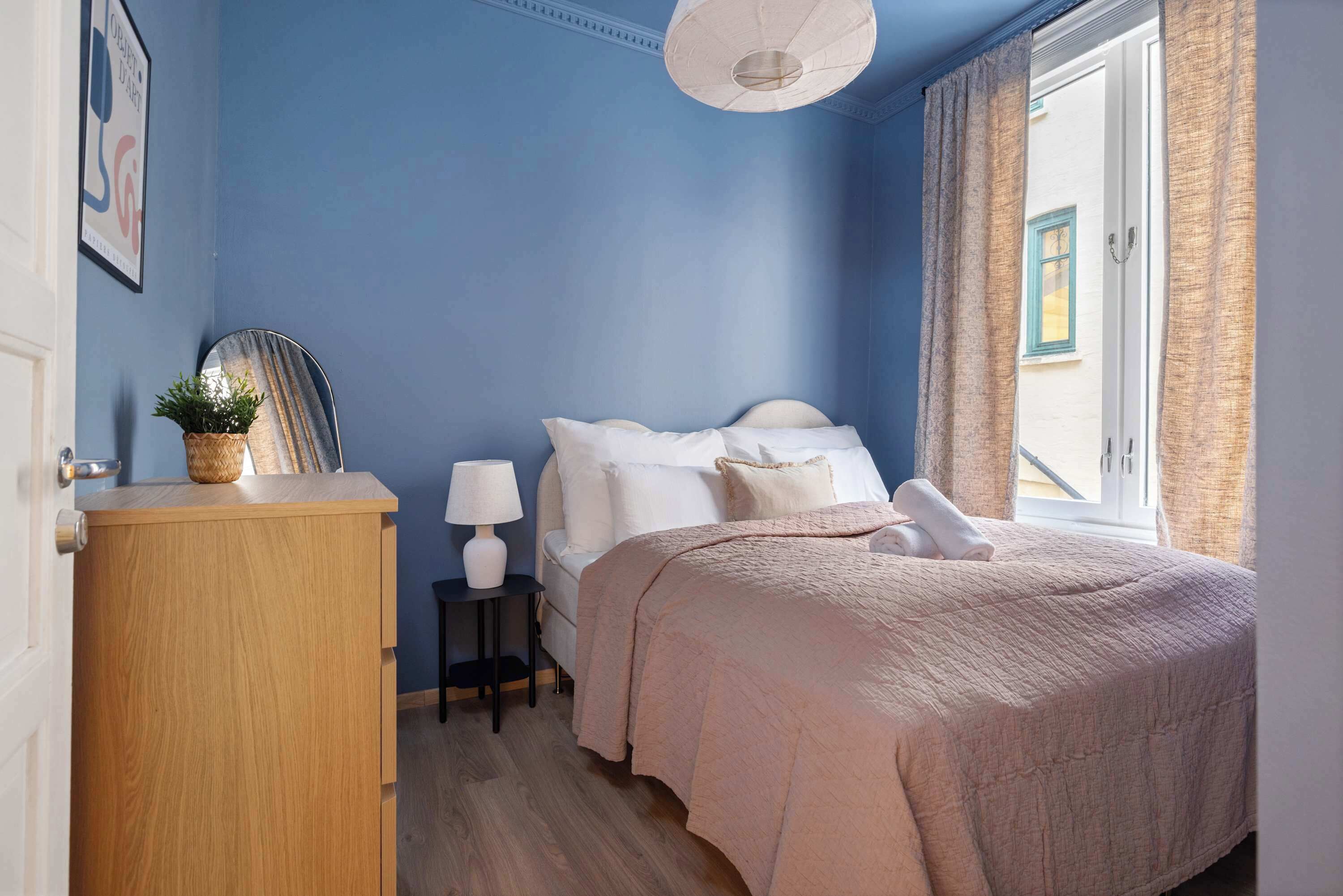 Una camera da letto con un letto, comodino, lampada e vista all'esterno.