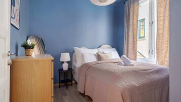 Una camera da letto con un letto, comodino, lampada e vista all'esterno.