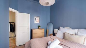A bedroom with a bed, a dresser, a mirror, and a door leading to another room.