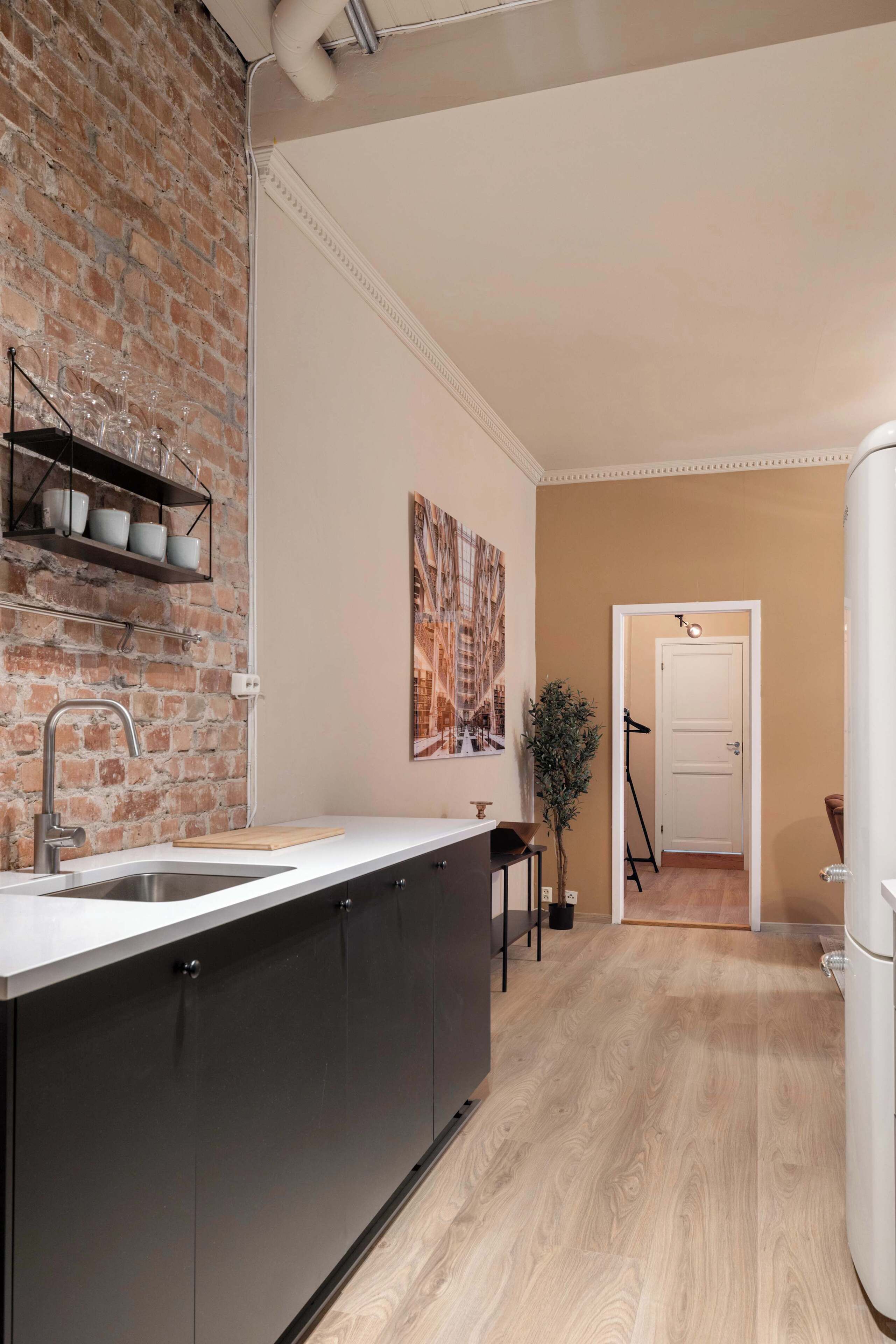 A modern kitchen with a brick wall, a large island, and a dining area with a table and chairs.