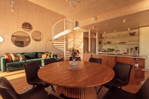 A modern interior with a wooden dining table, black chairs, a green sofa, and a spiral staircase leading to an upper level. - Stay North - Loviisa Floating House (Loviisa)
