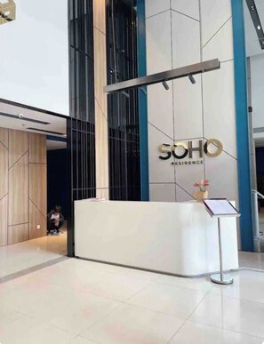 A reception desk with a modern design, a sign reading 'SOHO RESIDENCE,' and a small vase with flowers on top. - 3BR/4Beds | 2BA • Central D1 • Group Stay • Corner (Thành phố Hồ Chí Minh)