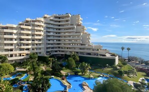 A multi-story hotel with a pool area and a view of the sea. - 1-Bedroom Apartment in Benalbeach with Pool, Private Terrace & Air Conditioning (Benalmádena)