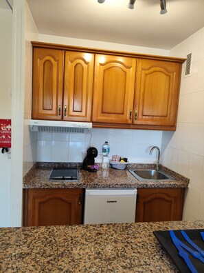 A kitchen with wooden cabinets, a built-in oven, a sink, and a dishwasher. - 1-Bedroom Apartment in Benalbeach with Pool, Private Terrace & Air Conditioning (Benalmádena)