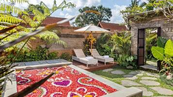 Un jardín con un parterre floral, dos sillones de descanso y un muro de piedra.