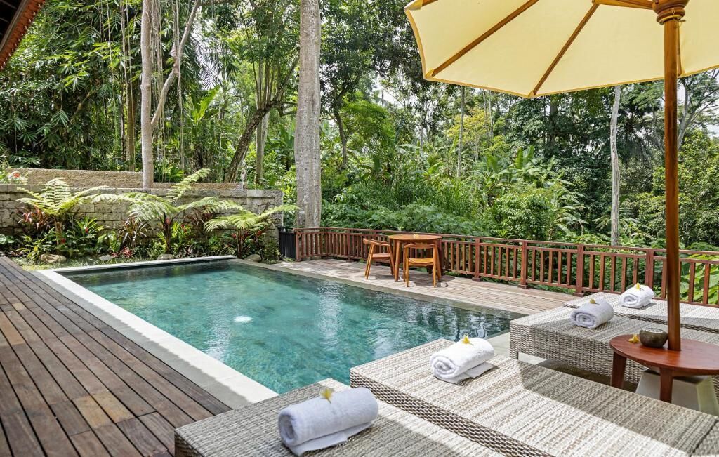 Un área de piscina con sillas de descanso y una terraza de madera.