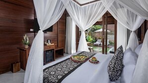 Un dormitorio con cama con dosel, un escritorio con silla y vistas al exterior.