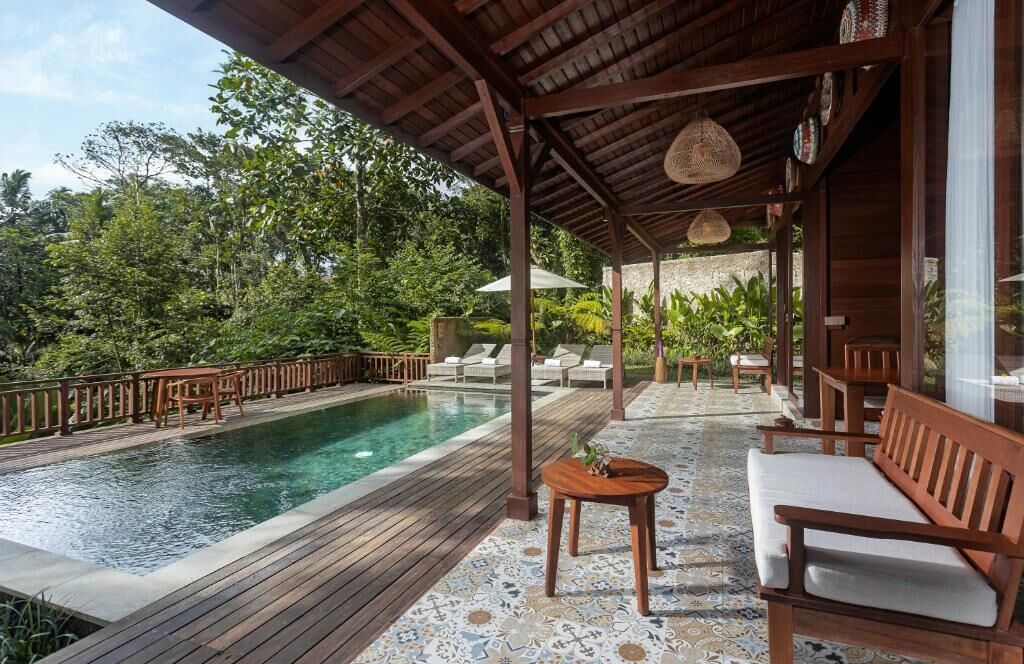 Un espace aménagé au bord de la piscine, avec une terrasse en bois, des chaises longues et un coin salon abrité.
