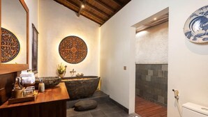 Un baño con lavamanos de piedra, tocador de madera y decoración en la pared.