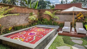A garden with a patterned flower bed, a brick wall with carvings, and a seating area with a canopy.